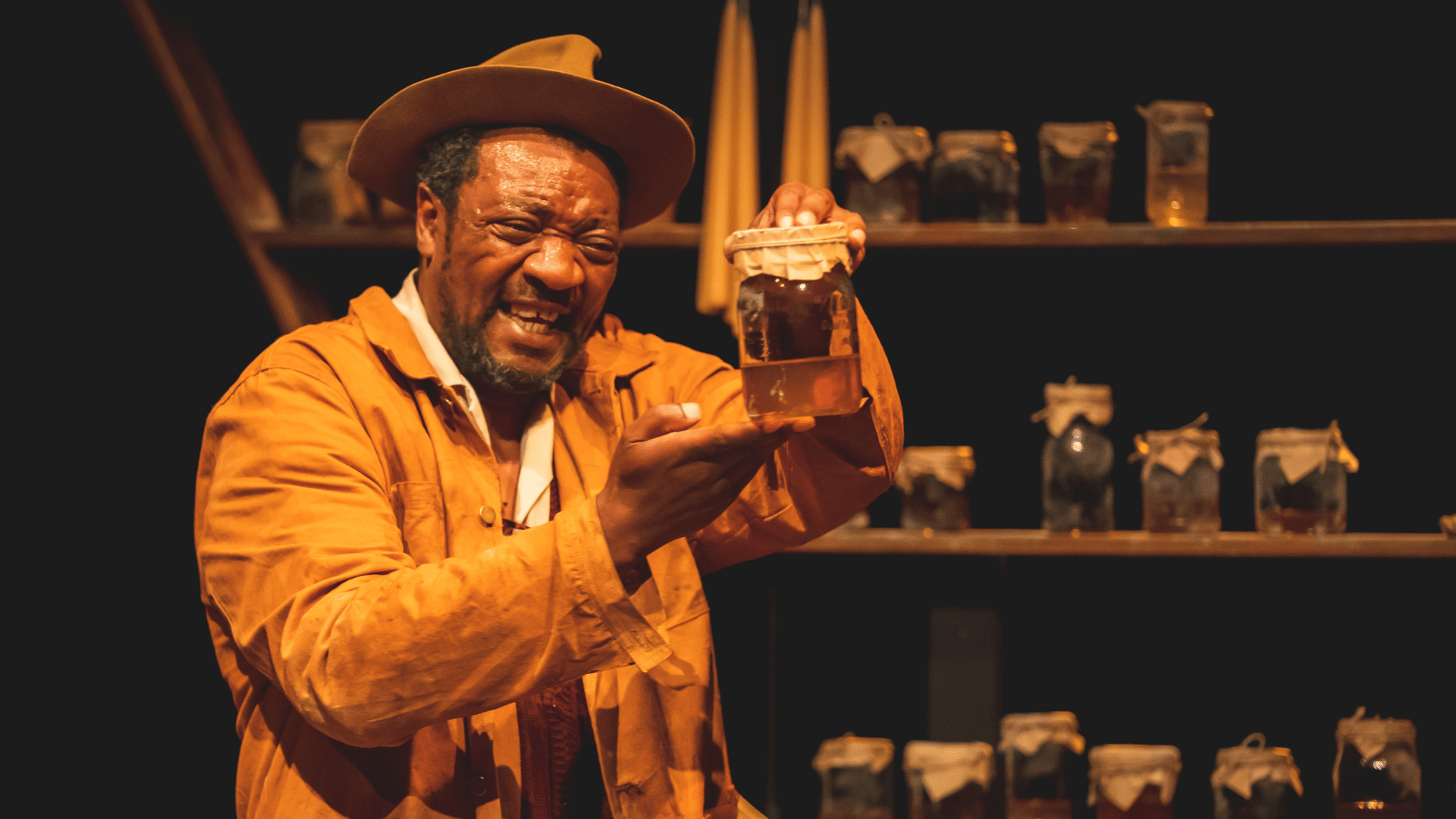 The Honey Man Production Photo: Honey Man (Everal Walsh) holds up a jar of honey while smiling