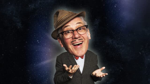 Count Arthur Strong promotional image - Count Arthur Strong with his head enlarged to be disproportionately big with the rest of his body. He wears a brown fedora hat, black horn-rimmed spectacles, a thin, neatly-trimmed moustache, red bow-tie, white shirt and grey suit jacket. He holds his hands in front of him and he smiles with a half-open mouth. Background: Starry image of space, with a celestial glow around Count Arthur Strong.