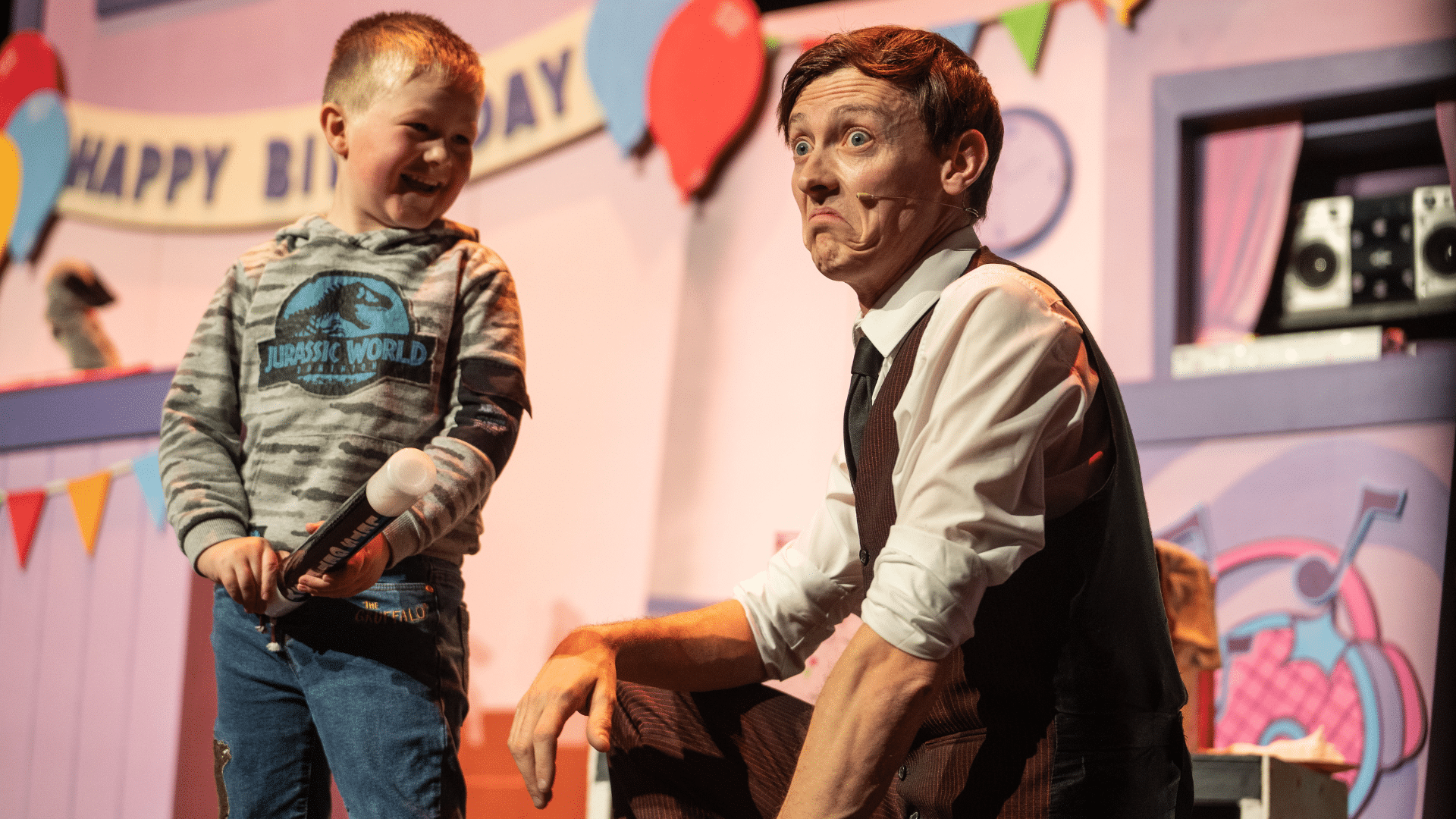The Sooty Show production image: a man in a brown pinstriped suit kneels next to a young boy, who is smiling.
