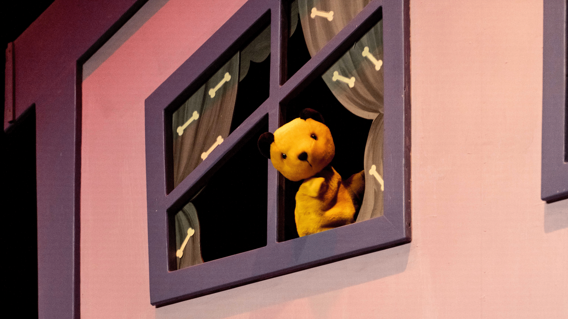 The Sooty Show production image: Sooty peers out of a purple window in the set.