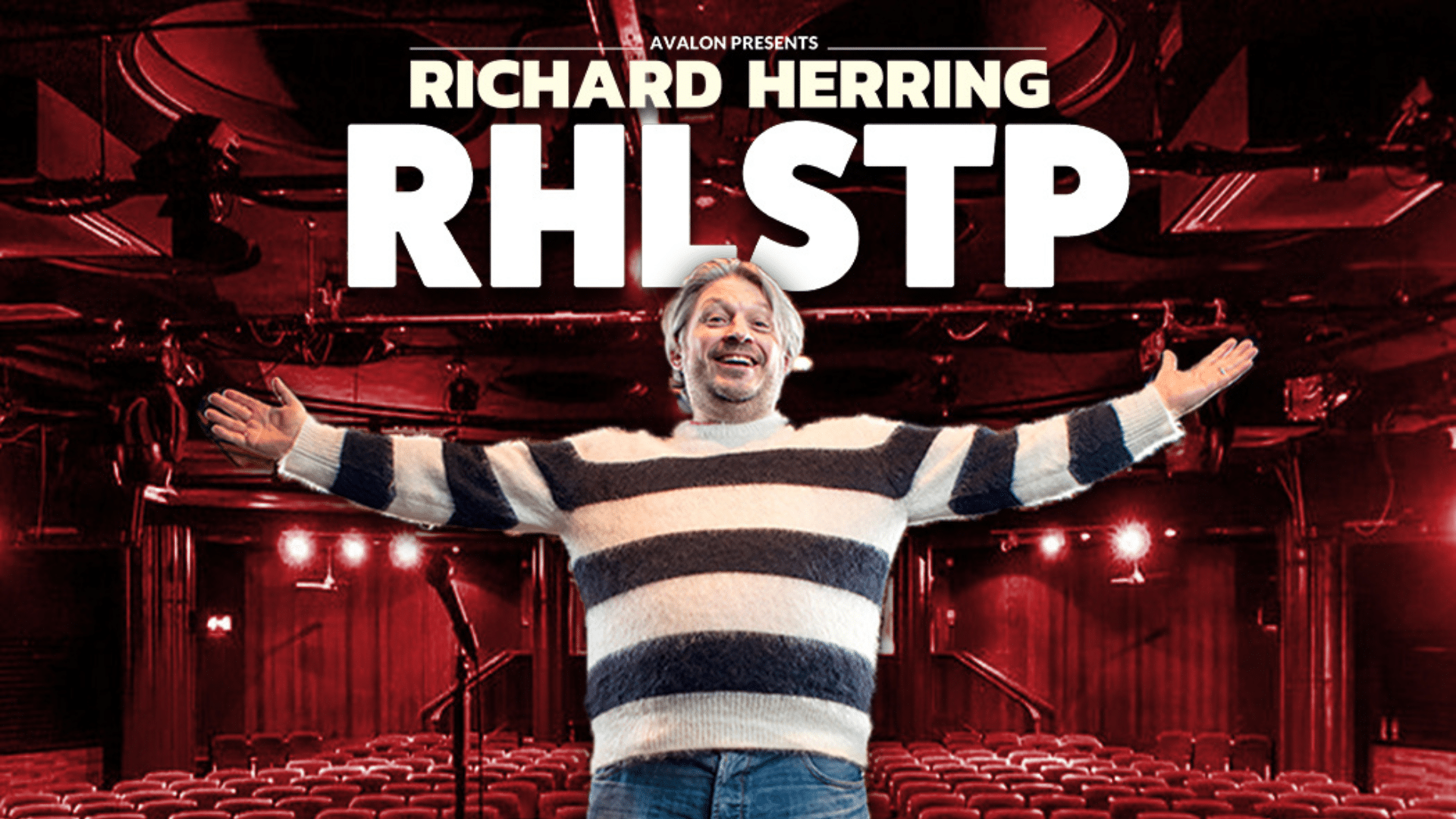 RHLSTP promotional artwork - Comedian Richard Herring, wearing a black and white striped jumper and blue jeans, stands facing forwards, with his arms outstretched in a welcoming pose. He wears a big smile on his face. Behind him is a microphone on a stand and an empty theatre auditorium. White text above reads: 'Avalon presents Richard Herring RHLSTP'.