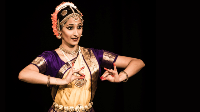 Vibha Selvaratnam dances on stage as an incarnation of Vishnu in a Indian dress and Bharatanatyam dance style.