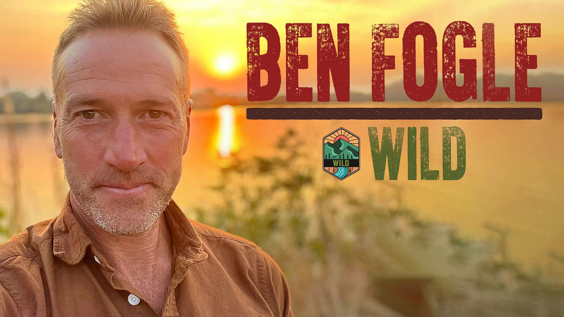Ben Fogle: Wild artwork. (Left) Ben Fogle, a middle-aged white man with grey stubble wearing a brown shirt, smiles while taking a selfie in front of a sunset over a lake. To their right, text reads: 'Ben Fogle. Wild.'