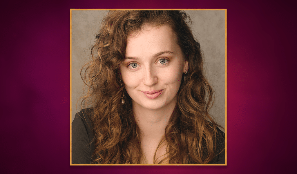 Headshot photo of actor Poppy Joy, a young white woman with light brown hair, wearing a green top. The headshot photo has a golden border around it, and is set on top of a purple gradient background.