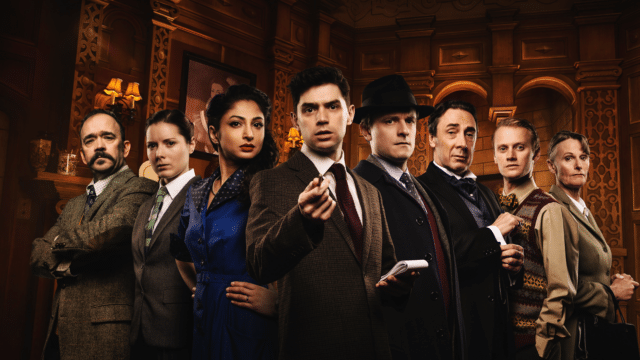 The Mousetrap promo image. Eight characters stand in a triangle formation, looking intently at the camera. A moustachioed man with crossed arms and a deeply-furrowed brow. A woman with slicked-back hair and a masculine suit, hands tucked behind her back. A woman in a peacock blue shirt-dress with her hands on her hips. A suited young man gesturing with a pen and holding a notebook. A man in a black felt hat looking concerned. A man in a silk cravat with a raised eyebrow. A man in a colourful knitted vest and bowtie, hands in pockets. A severe-looking woman in a beige overcoat pursing her lips.