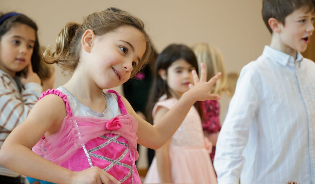 Photo of a little girl in a pink princess dress, dancing.