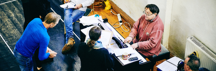 Rehearsal photo of Jack and the Beanstalk (2018) showing members of the cast and crew (including Paul McClure) gathered around a table and talking over scripts.