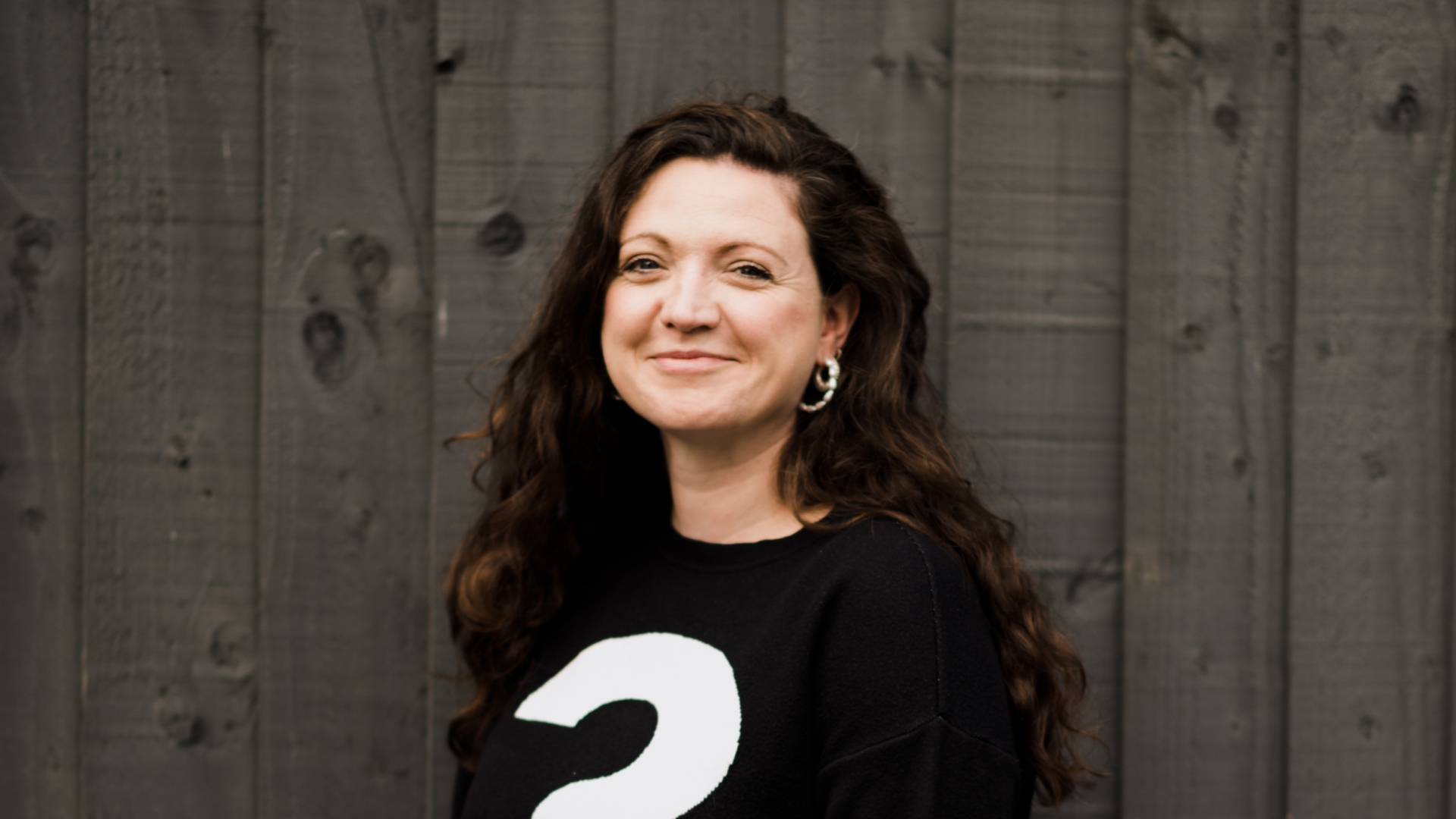 Headshot of a smiling Laura Horton against a wooden fence.