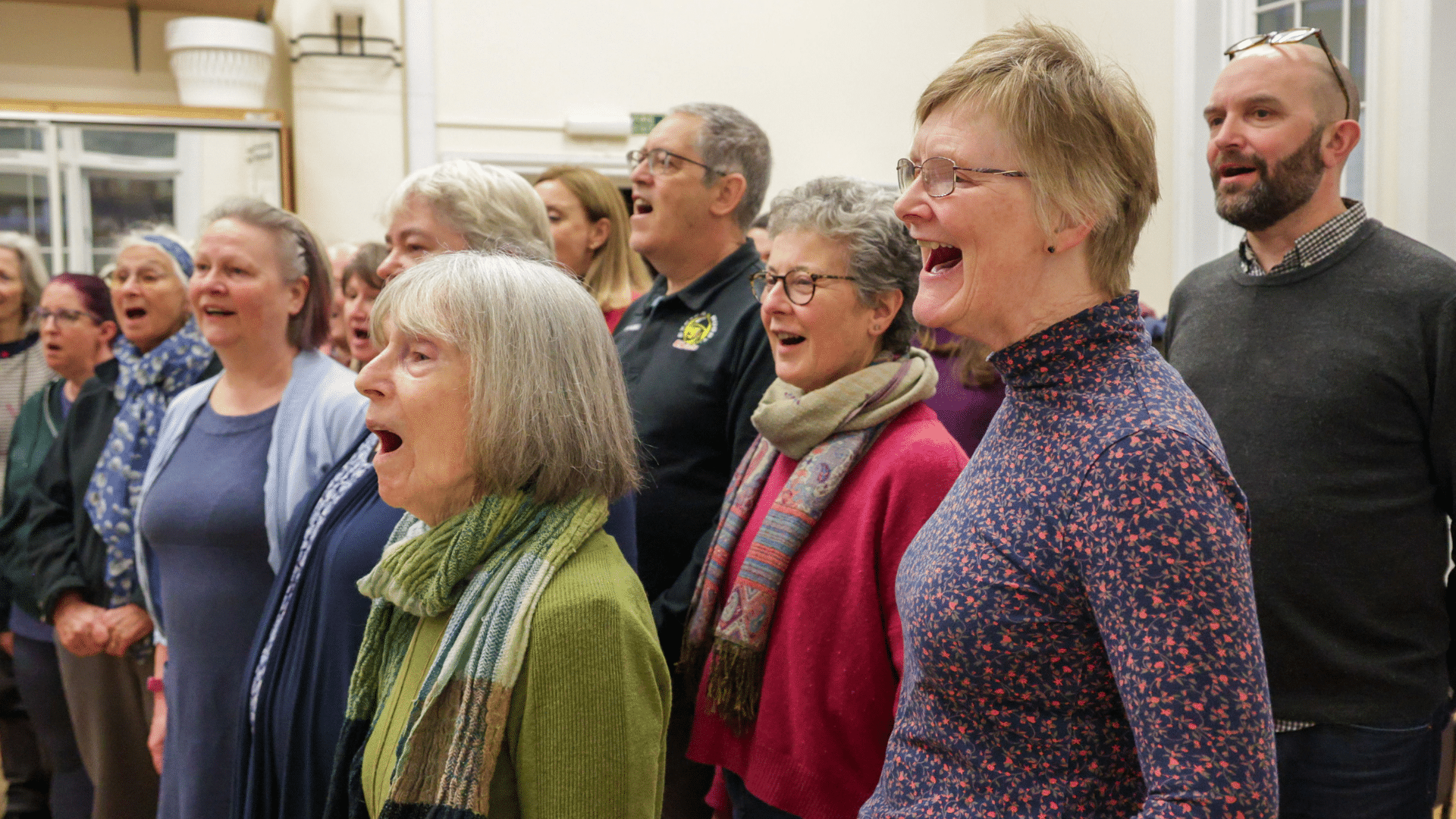 Image of the Northcott People's Choir. A group of people stand together singing.