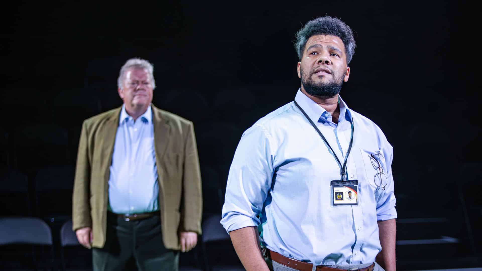 Exe Men production image. Emile Ruddock delivers a speech with Tim Hudson watching him.