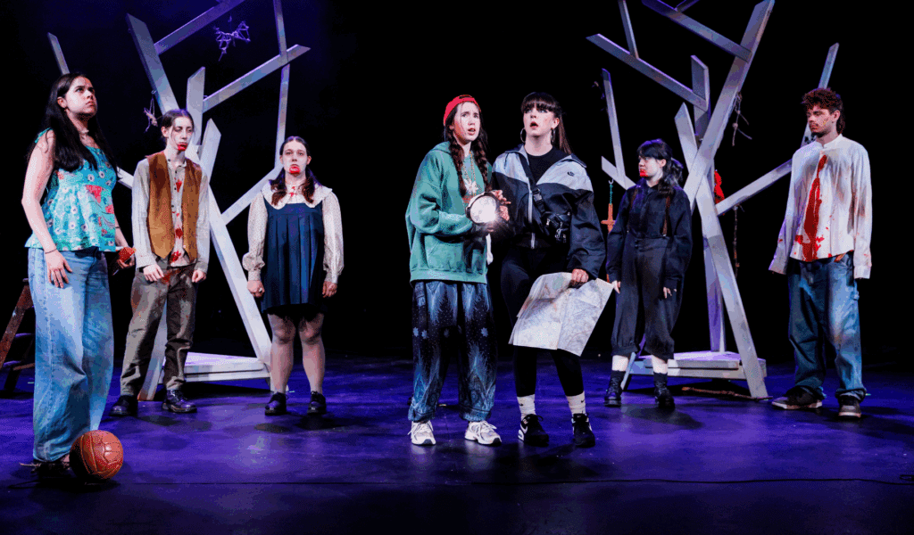Photo of seven young people acting on the Northcott stage. Some are spattered with crimson.