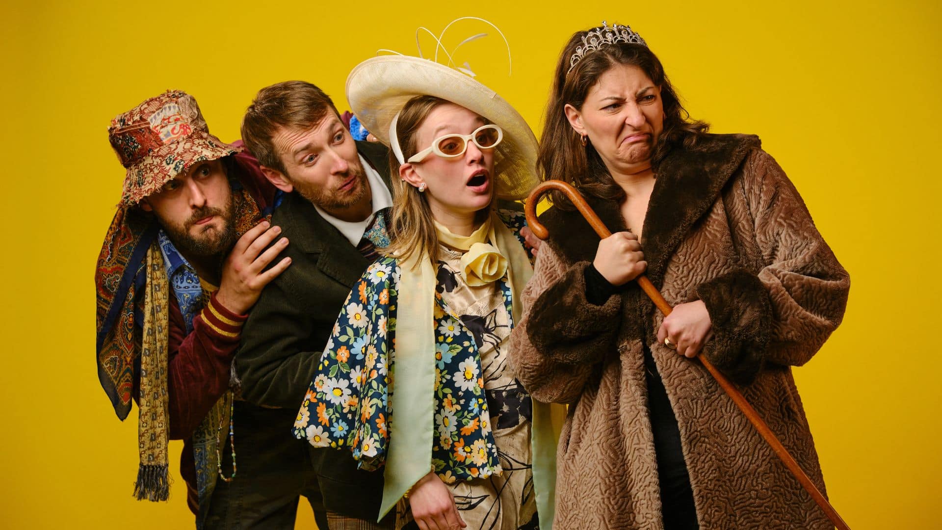 Madison Grace, Andrew Armfield, Jodie Micciché and Peter Watts pose in character against a yellow background.