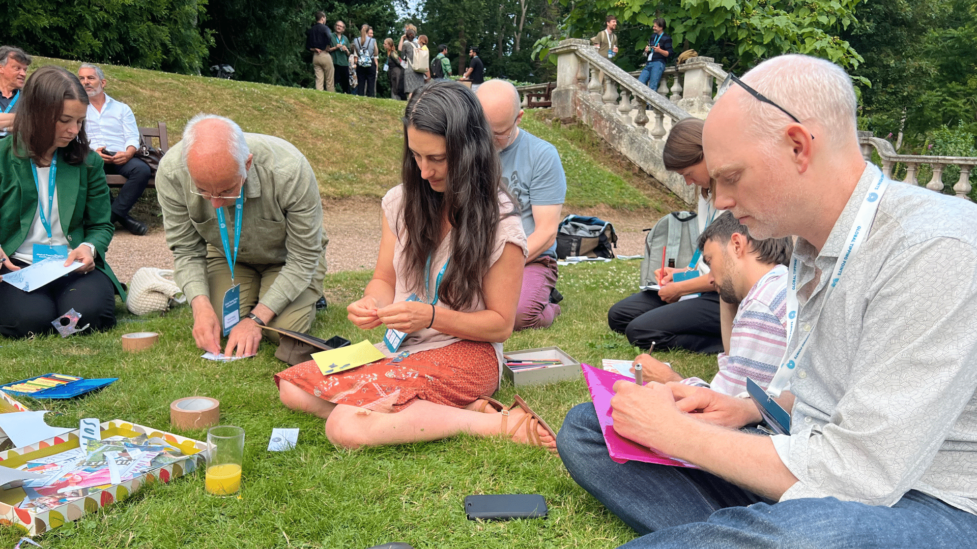 A photograph of participants sitting outside on grass taking part in a workshop.