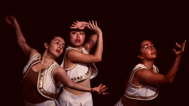 Three women dancing. They are wearing white, Persian-inspired costumes with gold trimmings.