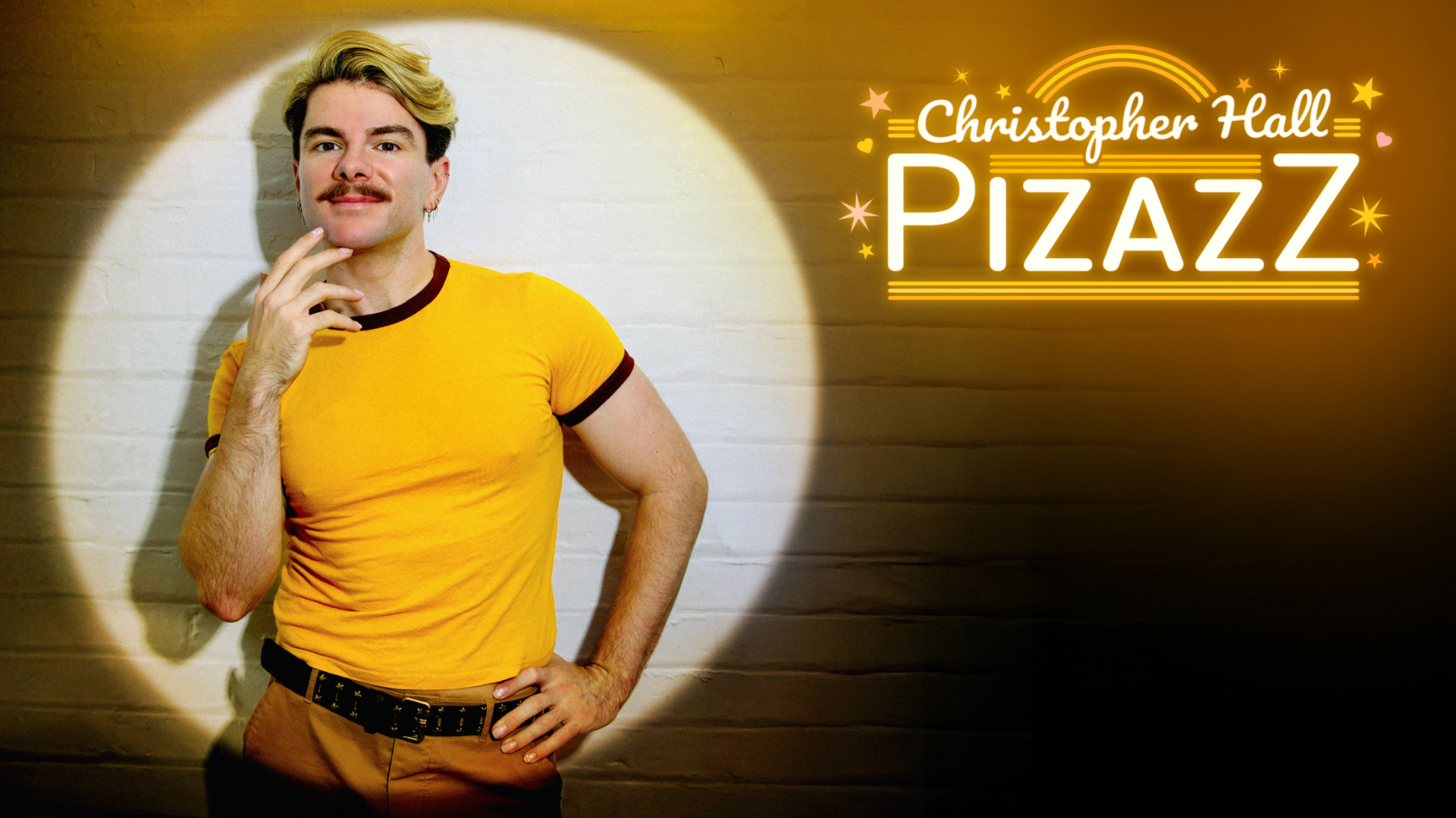 A photo of Christopher Hall stood against a white brick wall, smiling and lifting his hand to his chin. He is lit by a spotlight. Text reads: 'Christopher Hall. Pizazz'.