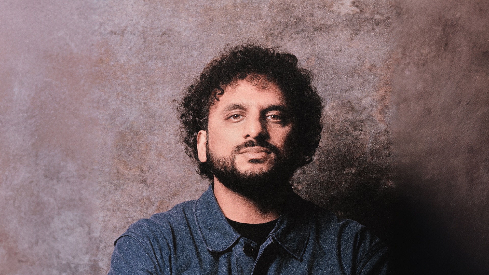 Image of Nish Kumar against a dappled pink background.