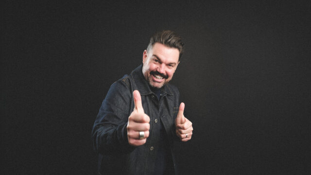 Charlie Baker smiles with both of his thumbs up.