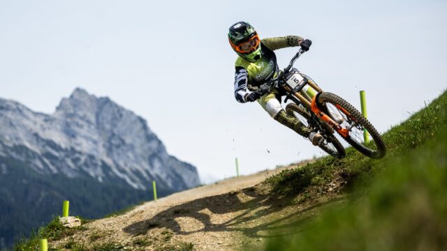 A photograph of Danny Hart riding a mountain bike on a green hill.