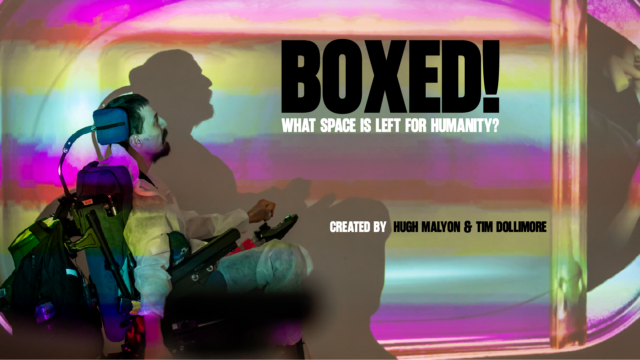A photograph of a bearded man steering an electric wheelchair. The space around him is lit in strips of colour. Text reads: 'Boxed! What space is left for humanity? Created by Hugh Malyon and Tim Dollimore'.