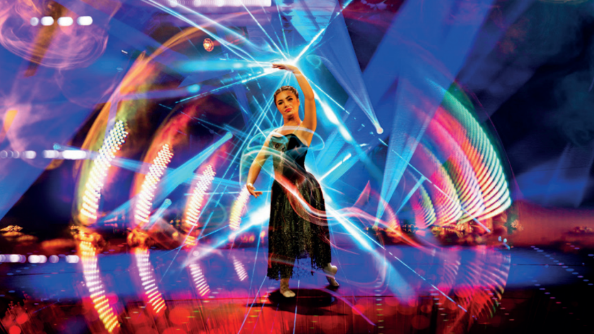 A photo of a woman on a stage dancing with lights swirling around her.