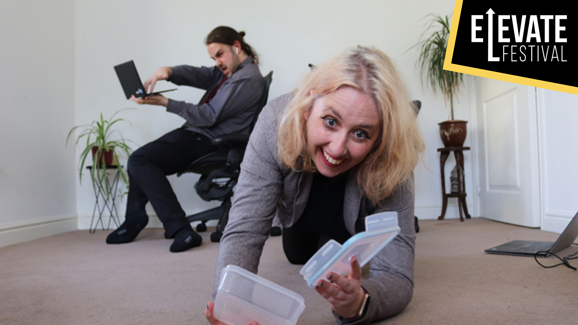 WORK artwork. A photo of a woman crawling on the floor holding a Tupperware. Behind her is a man sat on an office chair typing on a laptop.