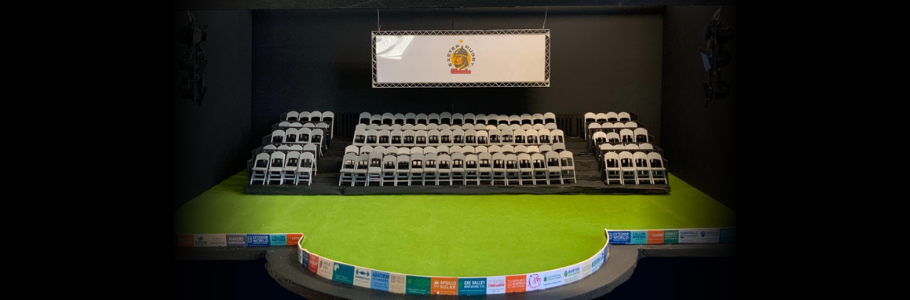 Photo of a model box of the Exe Men set, with the Northcott stage covered in turf, and backed by a grandstand.