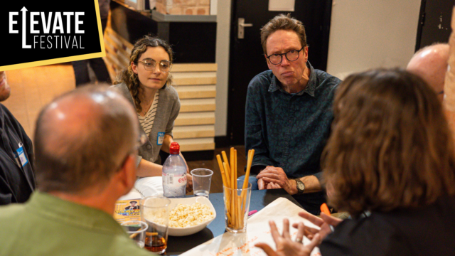 Image of artists sitting around a table having a discussion.