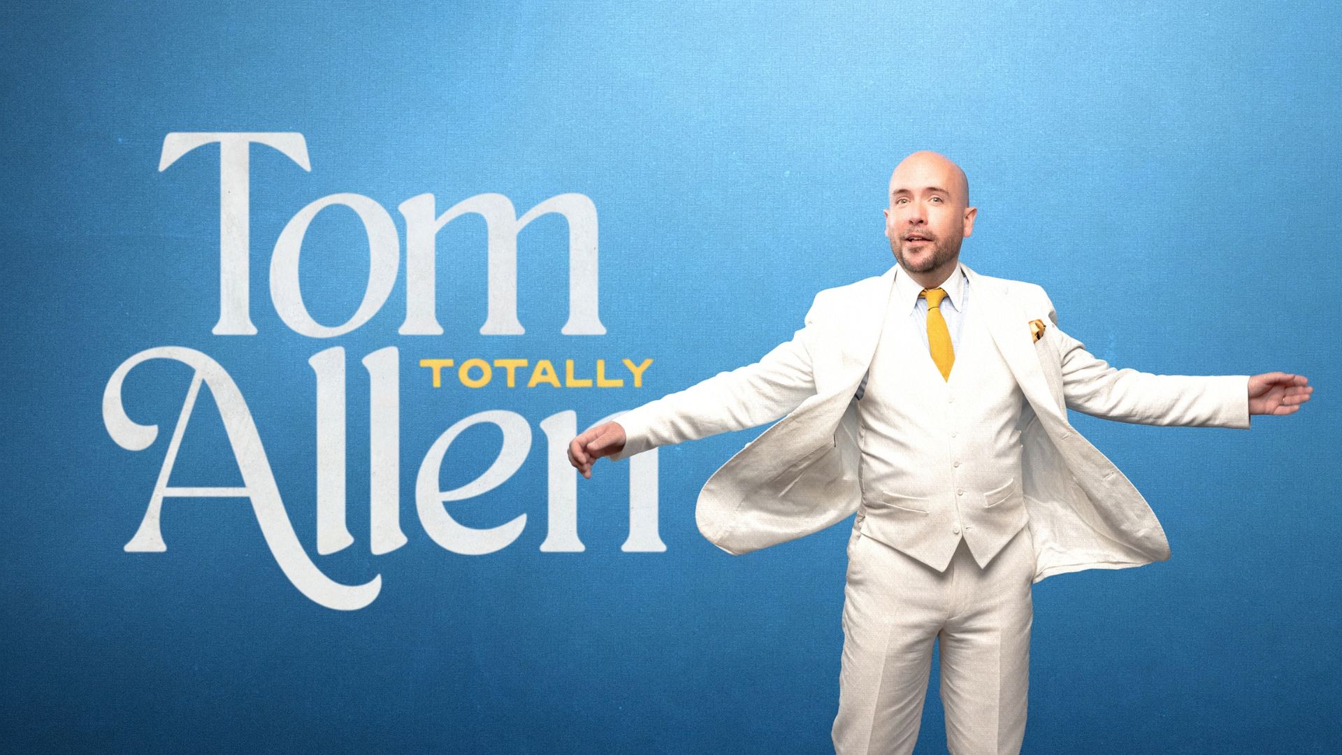 Tom Allen Totally promot artwork. A photo of Tom Allen behind a light blue background. He is wearing a white suit and gold tie. Text reads: Tom Allen Totally